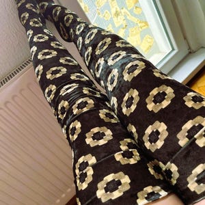 May include: Black velvet thigh-high stockings with a geometric pattern in gold.