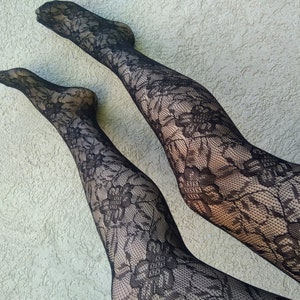 Può includere: Un paio di collant in pizzo nero con un motivo floreale. I collant sono trasparenti e hanno un design delicato.