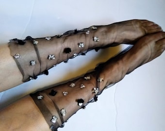 Peut inclure: Une paire de bas en résille noire avec des embellissements argentés et noirs. Les bas sont faits d'un tissu délicat et transparent et ont un aspect brillant et festif.