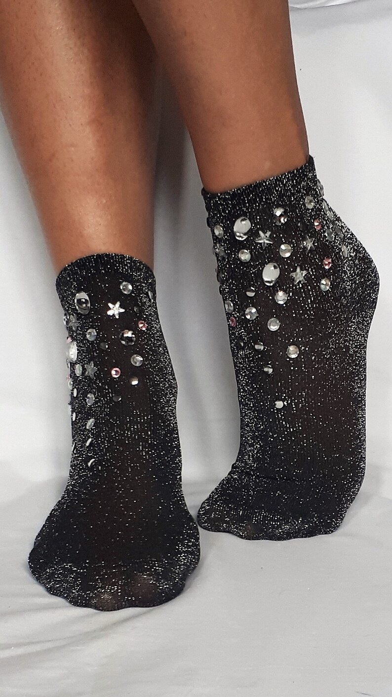 May include: A pair of black sparkly socks with silver and pink embellishments. The socks are ankle-length and have a glittery finish.