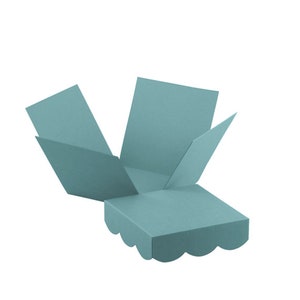 May include: A teal-coloured explosion box, open to reveal its interior. The box has a square base with scalloped edges and four flaps extending outwards. The box is made of paper and is designed to open up.
