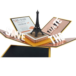 Può includere: Un biglietto pop-up decorativo con una statuetta della Torre Eiffel nera, dettagli oro e oro rosa e le parole "SAVE THE DATE". Il biglietto include un invito stampato con nomi e dettagli dell'evento.