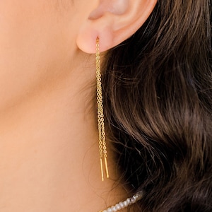 May include: A pair of gold chain earrings with a small bar at the end of each chain.