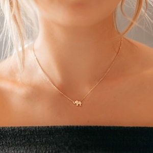 May include: A gold chain necklace with a small elephant pendant.