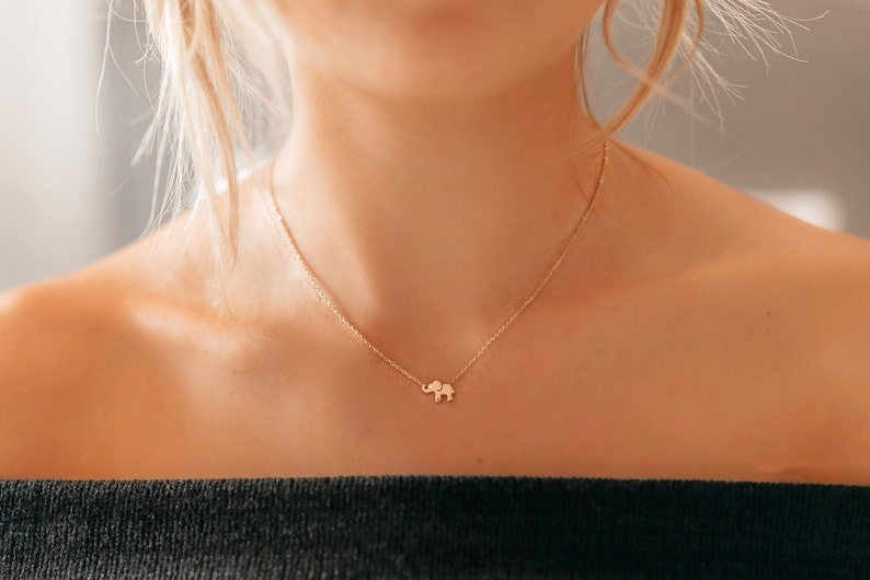 May include: A gold chain necklace with a small elephant pendant.