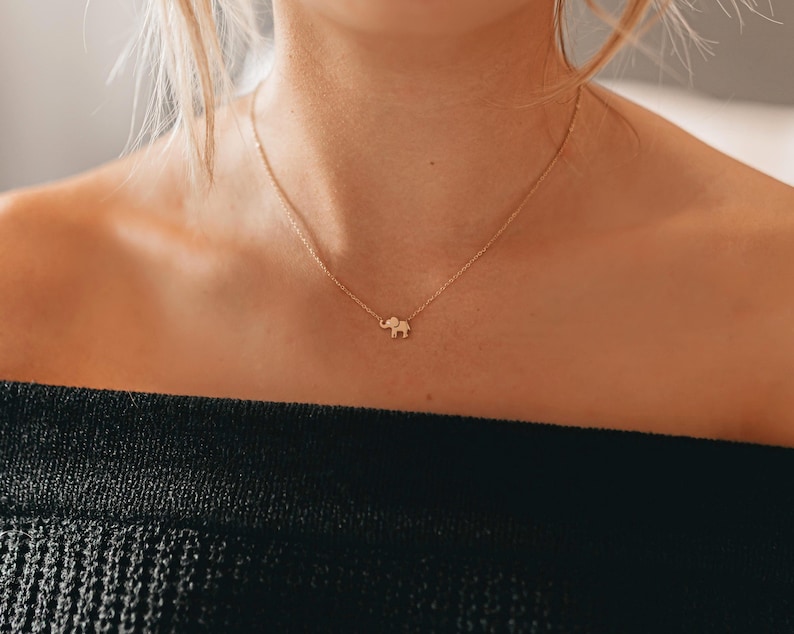 May include: A gold necklace with a small elephant pendant.