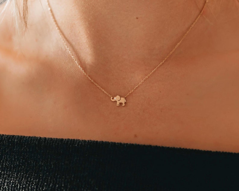 May include: A delicate gold chain necklace with a small elephant pendant.
