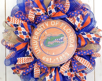 May include: A blue and orange University of Florida wreath with a wooden sign that says "University of Florida est. 1853".