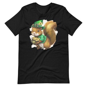 May include: A black t-shirt with a graphic of a squirrel wearing a green leprechaun hat and holding a pot of gold. The squirrel is peeking out of a torn hole in the shirt.
