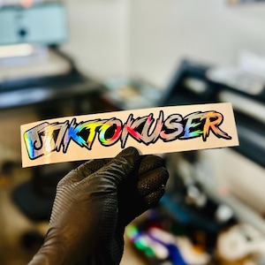 May include: A sticker with the word "TIKTOUSER" written in a rainbow gradient font with a jagged, edgy style.