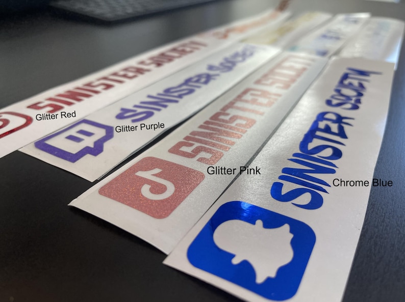 May include: A collection of four rectangular adhesive decals featuring the text SINISTER SOCIETY and various social media icons. The decals are available in glitter red, glitter purple, glitter pink, and a reflective chrome blue finish.