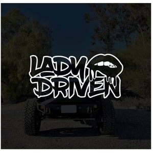 Pu&ograve; includere: Un adesivo grafico in bianco e nero con il testo "Lady Driven" in un font in stile graffiti. Un'immagine stilizzata in bianco e nero di un rossetto che cola &egrave; sopra il testo.