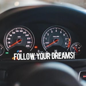 May include: A close-up of a car's dashboard with two gauges. The speedometer reads 0 km/h and the tachometer reads 0 rpm. The text "FOLLOW YOUR DREAMS!" is displayed on the dashboard.
