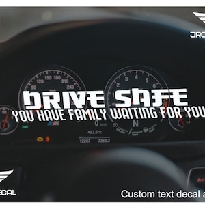 May include: A black and white car dashboard decal with the text "DRIVE SAFE YOU HAVE FAMILY WAITING FOR YOU". The decal is designed to be placed on a car dashboard.