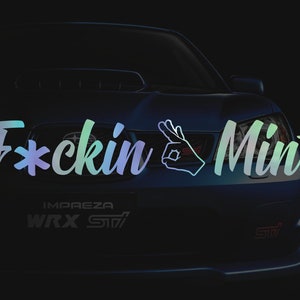 May include: A blue Subaru Impreza WRX STI with the text "F*ckin' Mint" in a rainbow gradient on the front bumper. The car has a white outline of a hand making the "OK" sign.
