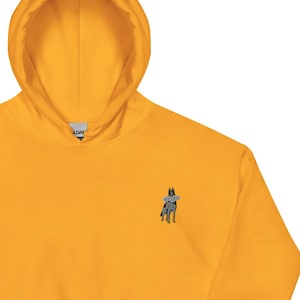 May include: Mustard yellow hoodie with a kangaroo pocket and drawstring hood. Features a small embroidered design on the chest. The hoodie is made of a soft material.