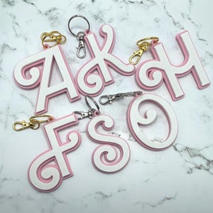 Etiqueta para bolso con llavero y letra rosa y blanca