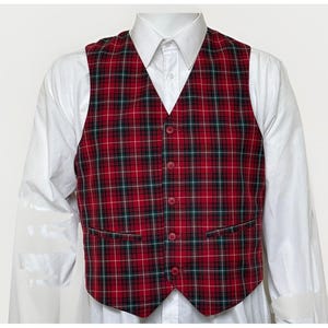 May include: A red plaid vest with green and white accents, featuring a button-up front and two front pockets. The vest is worn over a white collared shirt, creating a classic and stylish look.