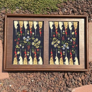 May include: A rectangular wooden frame containing two side-by-side panels of dark blue fabric. Each panel features a repeating pattern of white unicorns, red and gold decorative elements, and various colourful floral motifs in a symmetrical layout.