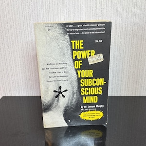 May include: A vintage paperback book titled "The Power of Your Subconscious Mind" by Dr. Joseph Murphy. The cover is black and white with the title in large yellow letters. The book promises to help readers win riches, gain youthfulness, and find inner strength.