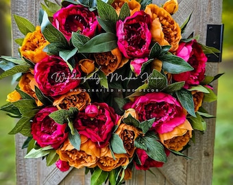 May include: A vibrant pink and orange peony wreath with green leaves. The wreath is hanging on a wooden door with a black latch. The text "Wonderfully Made Yours" and "Handcrafted Home Decor" is visible on the wreath.