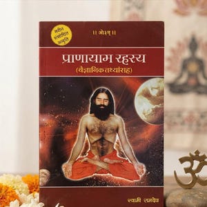 May include: A book titled Pranayam Rahasya with a dark red cover featuring a central illustration of a person with a beard sitting in a meditative pose, wearing orange clothing, against a cosmic background with a moon and Hindi text.