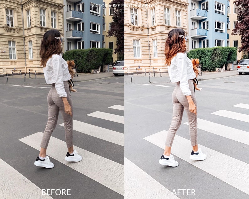 May include: A woman wearing a white cropped shirt, plaid pants, and white sneakers walks across a crosswalk with a small dog. The woman is wearing sunglasses and has long brown hair.
