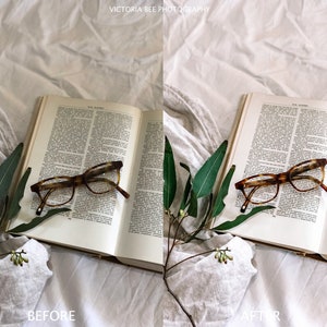 May include: A book with a pair of tortoiseshell glasses resting on top of it. The book is open and the pages are filled with text. A sprig of green leaves is on the left side of the book. The book and glasses are on a white linen surface.