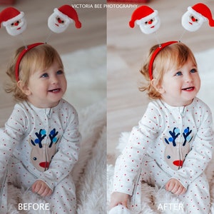 Pode incluir: Uma crian&ccedil;a pequena vestindo um macac&atilde;o de rena branco e vermelho com uma faixa de cabe&ccedil;a vermelha com dois chap&eacute;us de Papai Noel no topo. A crian&ccedil;a est&aacute; sentada em uma superf&iacute;cie branca e fofa e sorrindo.
