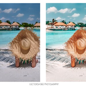 May include: A woman wearing a large, brown straw hat sits on a white sandy beach with turquoise water in the background.  The beach is in front of a tropical island with several buildings.