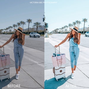 May include: A woman in a light blue jumpsuit and a straw hat is standing on a sidewalk with a suitcase and a pink Chanel bag. She is looking at the camera. The background is a street with palm trees and cars.