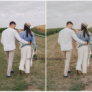 May include: A family of three walks through a field, the parents are wearing white shirts and the woman is wearing a straw hat. The child is being carried by the woman.