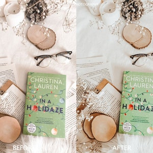 May include: A flat lay image of a book titled "In a Holidaze" by Christina Lauren. The book is on a white surface with white flowers, a wooden coaster, and a pair of eyeglasses. The book cover is green with a Christmas lights design and a red ornament.