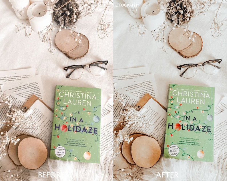 May include: A flat lay image of a book titled "In a Holidaze" by Christina Lauren. The book is on a white surface with white flowers, a wooden coaster, and a pair of eyeglasses. The book cover is green with a Christmas lights design and a red ornament.
