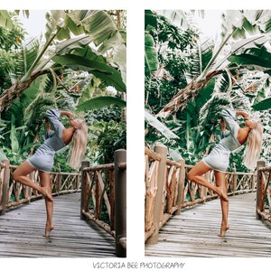 May include: A woman in a light blue dress poses on a wooden bridge surrounded by lush green foliage. The bridge is made of wooden planks and has a railing on either side. The woman is standing on the bridge with her arms raised above her head. The foliage is thick and green, and the sun is shining through the leaves.