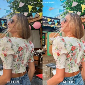 May include: A woman wearing a white floral print crop top with puff sleeves and blue jeans. She is standing outdoors with a string of colorful flags hanging overhead.