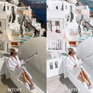 May include: A woman wearing a white robe sits on a white ledge overlooking a white and blue town. The woman is wearing sunglasses and has her hair pulled back. The town is built into the side of a cliff and the sea is visible in the background.