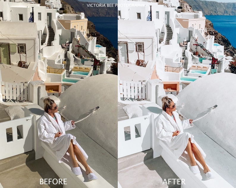 May include: A woman wearing a white robe sits on a white ledge overlooking a white and blue town. The woman is wearing sunglasses and has her hair pulled back. The town is built into the side of a cliff and the sea is visible in the background.