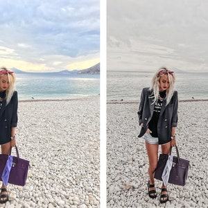 May include: A woman wearing a black blazer, a black t-shirt with white text, denim shorts, and a red bandana on her head. She is carrying a purple handbag with a light purple scarf hanging out of it. She is standing on a pebble beach with a body of water in the background.