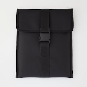 Puede incluir: Una funda para portátil negra con una correa negra y un cierre de hebilla.