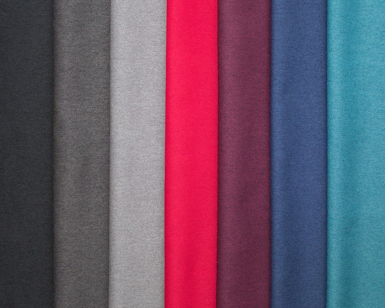 May include: A collection of fabric swatches in various colors, including black, gray, red, purple, blue, and teal. The fabric appears to be a smooth, solid material, possibly for apparel or home decor.