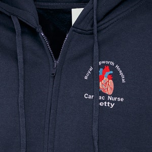 May include: A navy blue zip-up hoodie with a white embroidered design featuring a heart, the text "Royal  pworth Hospital Cardiac Nurse" and a red and blue anatomical heart.