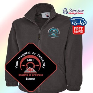 K&ouml;nnte beinhalten: Anthrazitfarbene Fleecejacke mit Rei&szlig;verschluss und gesticktem MRI-Design. Die Jacke hat einen hohen Kragen, einen durchgehenden Rei&szlig;verschluss und ein kleines gesticktes Logo auf der Brust. Das Design enth&auml;lt den Text "Your Hospital or University MRI Imaging in progress Name".