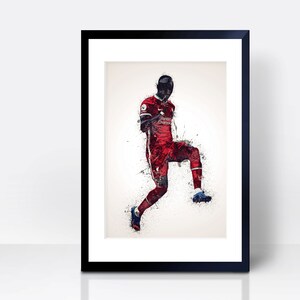 May include: A digital art print of a soccer player in a red and white uniform with black shorts, kicking a soccer ball. The player is in mid-air and the background is a white splatter effect.