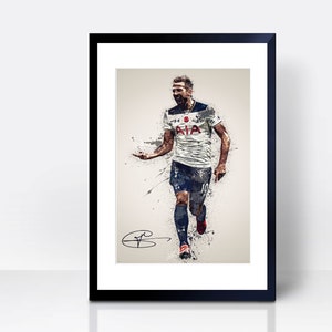 May include: A black and white watercolour illustration of a football player in a white shirt with blue accents, running and celebrating a goal. The player is wearing black shorts and red and white boots. The shirt has the text "AIA" on the front. The image is framed in a black frame with a white mount.