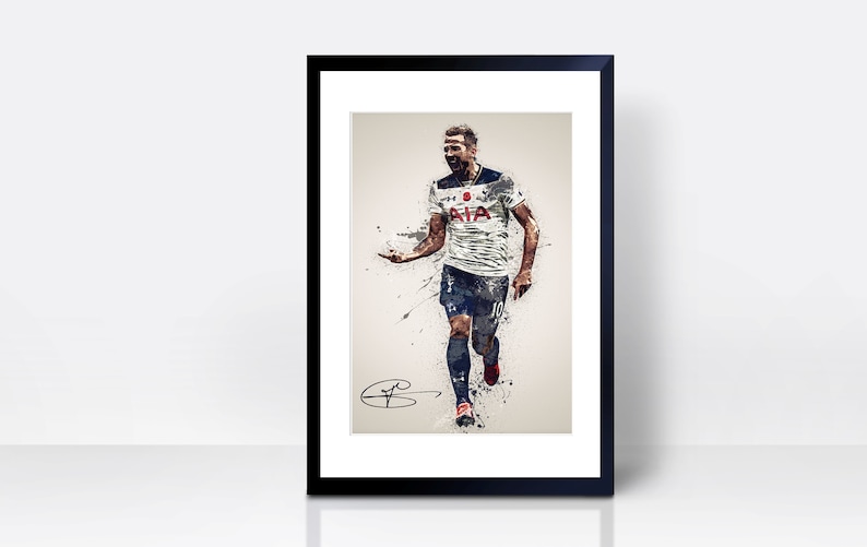 May include: A black and white watercolour illustration of a football player in a white shirt with blue accents, running and celebrating a goal. The player is wearing black shorts and red and white boots. The shirt has the text "AIA" on the front. The image is framed in a black frame with a white mount.