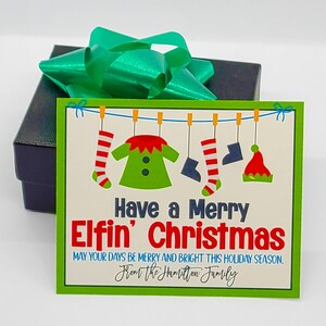 May include: A green and white gift card with a Christmas elf design. The card reads "Have a Merry Elfin' Christmas" and "May your days be merry and bright this holiday season. From the Hamilton Family."