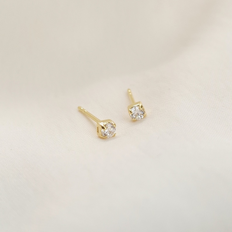 a pair of 18k gold plated stud earrings with a cubic zirconia stone in the middle