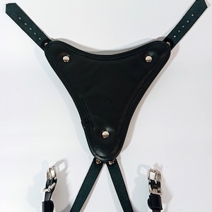 May include: Black leather harness with a triangular shaped piece in the front. The harness has two straps that connect to the triangular piece and two straps that connect to the back. The straps have silver buckles.