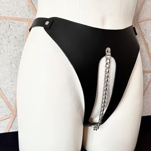 May include: Black leather lingerie with a silver chain detail.